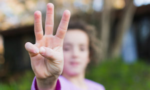 girl showing three finger salute 