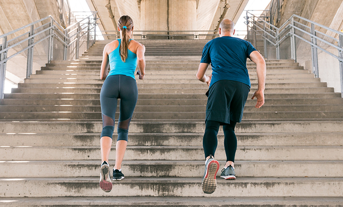 rear view male-female athlete jogging staircase