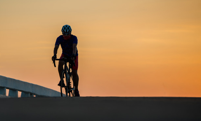 silhouette-man-rides-bike-sunset-orange-blue-sky-background-cycling